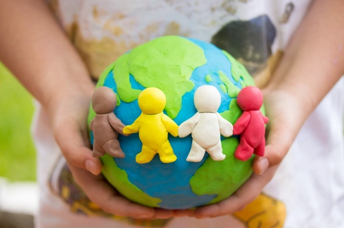 child's hands holding clay model of the world