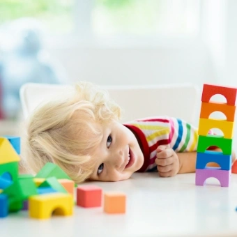 curly blond child stacking wooden blocks