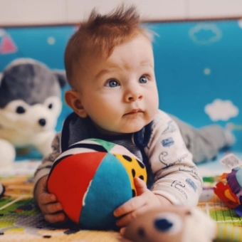 baby boy laying on the floor playing with stuffed toys