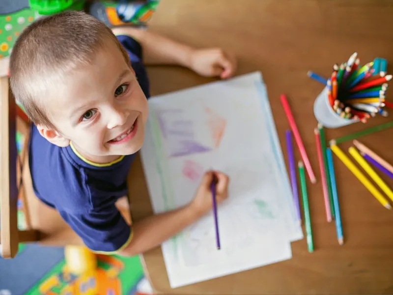 young child drawing with colored pencils
