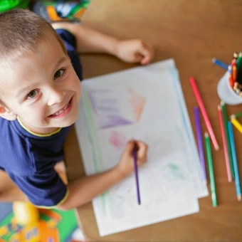 young child drawing with colored pencils
